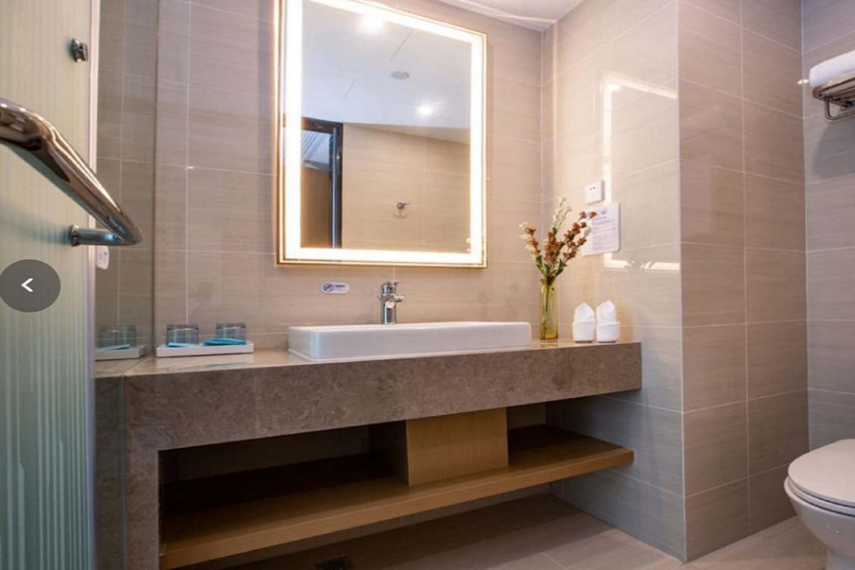 A modern bathroom with a large mirror, a sink, a toilet, and a shower area.
