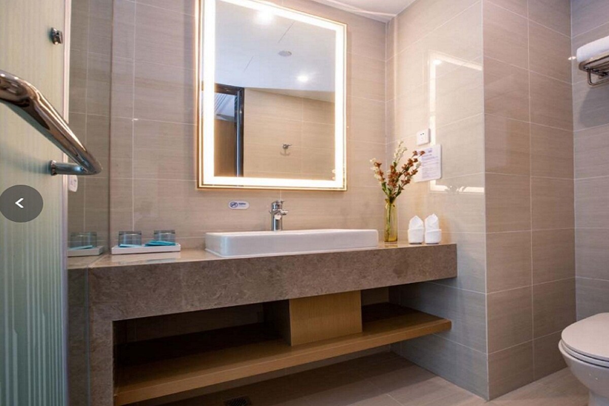A modern bathroom with a large mirror, a sink, a toilet, and a shower area.