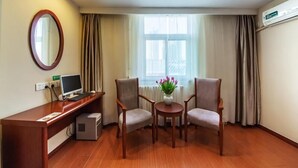 A hotel room with a wooden desk, two chairs, a small table with flowers, a mirror, and a window with curtains. - Greentree Inn Liaocheng Gaotang Tianqi Temple Business Center Express Hotel (Liaocheng)
