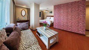 A hotel room with a sofa, a coffee table, a bed, and a brick accent wall. - Greentree Inn Liaocheng Gaotang Tianqi Temple Business Center Express Hotel (Liaocheng)