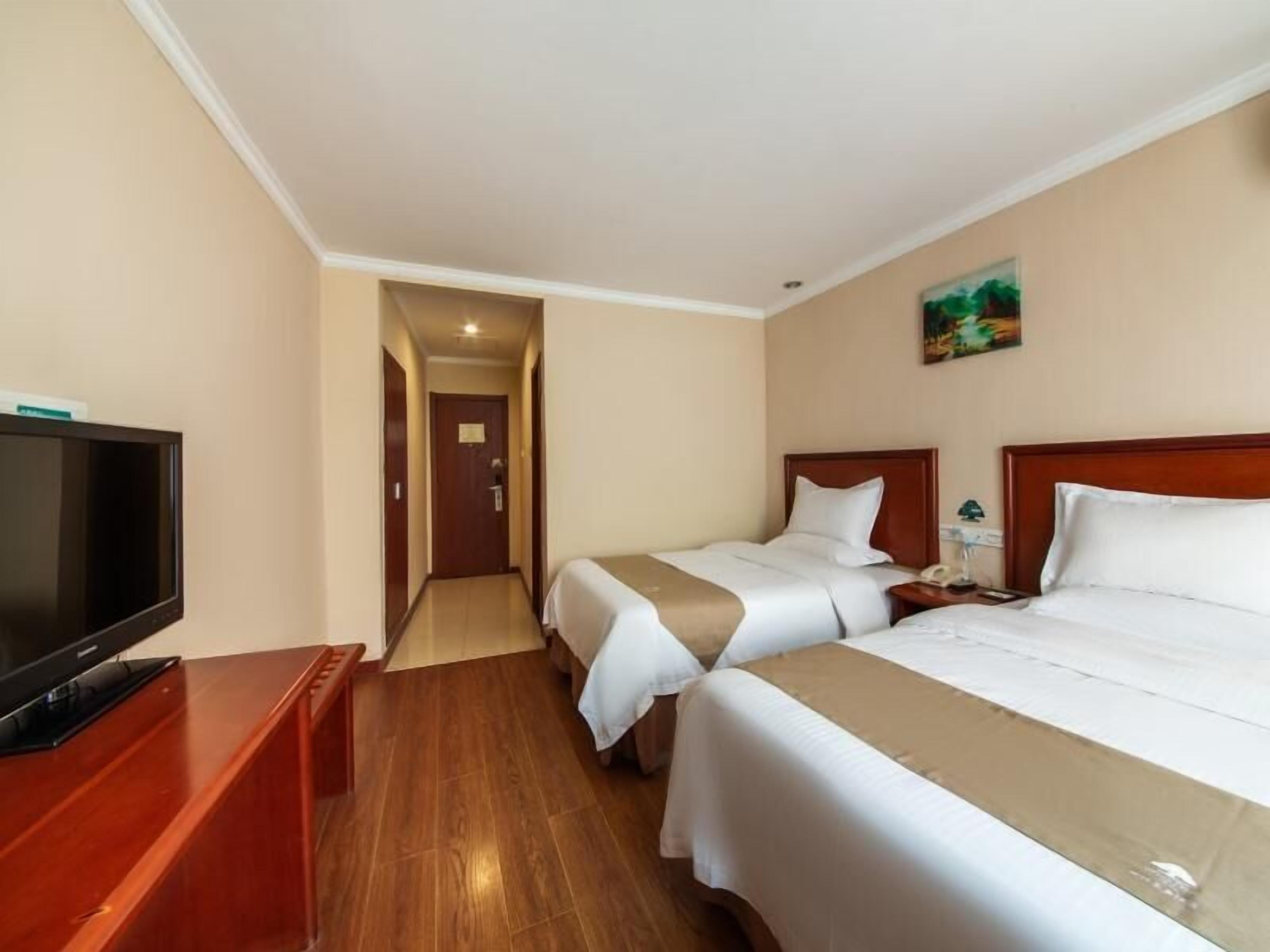 A hotel room with two beds, a television, and a painting on the wall.