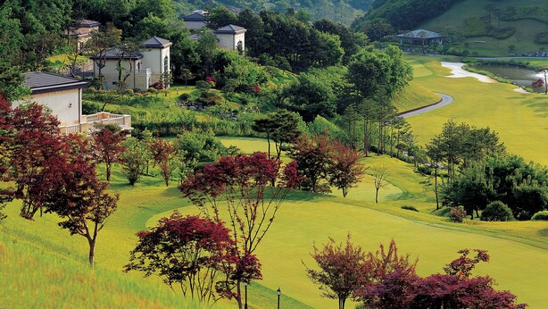 A serene landscape with a golf course, a small cluster of buildings, and a river. - Crystal Valley CC - Golden Village (Gapyeong)