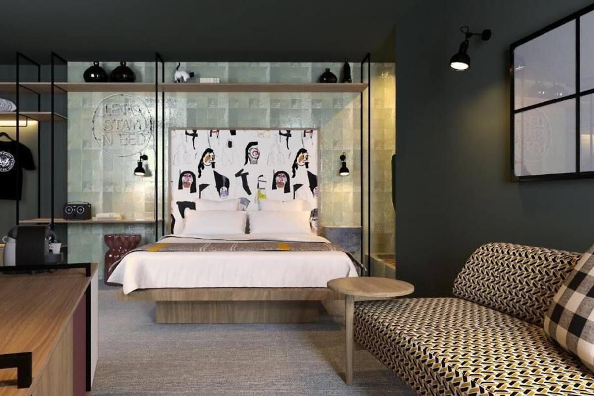 A modern bedroom with a bed, a sofa, a desk, and a glass partition.