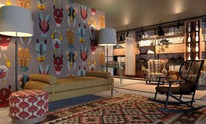 A cozy living room with a patterned wall, a sofa, a rocking chair, and a bookshelf filled with books and decorative items. - Se Catedral Hotel Porto, Tapestry Collection by Hi (Porto)