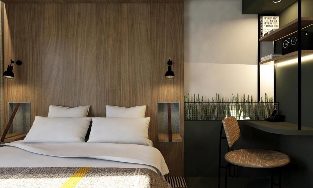 Moderni hotellihuone, jossa on puinen sängynpääty, valkoisilla lakanoiden peitetty sänky, kaksi yöpöytävalaisinta, pieni pöytä tuolilla sekä näkymä bambuaitaan.