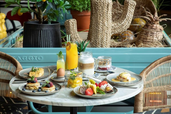 A breakfast table with various dishes, a potted plant, and wicker baskets. - Se Catedral Hotel Porto, Tapestry Collection by Hi (Porto)
