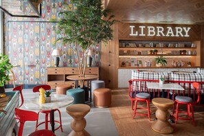 A cozy library with a wooden ceiling, bookshelves, a red and blue seating area, and a plant. - Se Catedral Hotel Porto, Tapestry Collection by Hi (Porto)