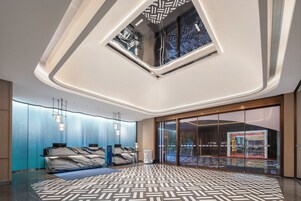 Un moderno vestíbulo de hotel con una recepción de mármol, piso estampado y tragaluces.
