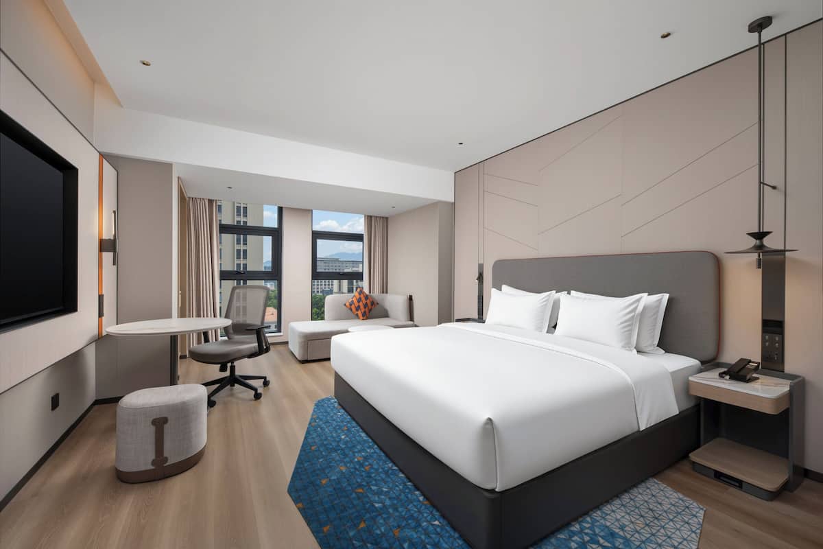 Een moderne hotelkamer met een groot bed, een bureau, een stoel en een televisie.