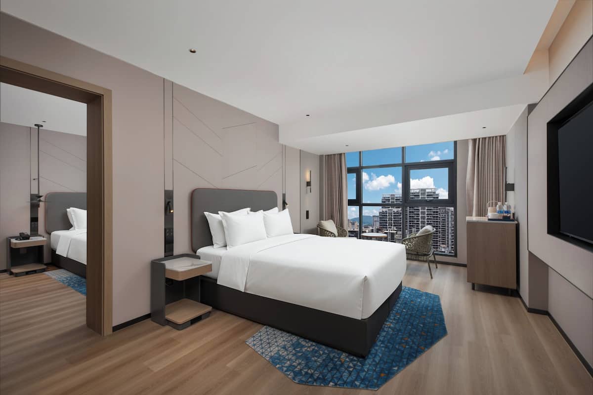 Een moderne hotelkamer met een groot bed, een televisie, stadszicht en een balkon.