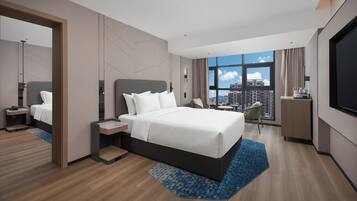 Una habitación de hotel moderna con una cama grande, televisión, vistas a la ciudad y un balcón.