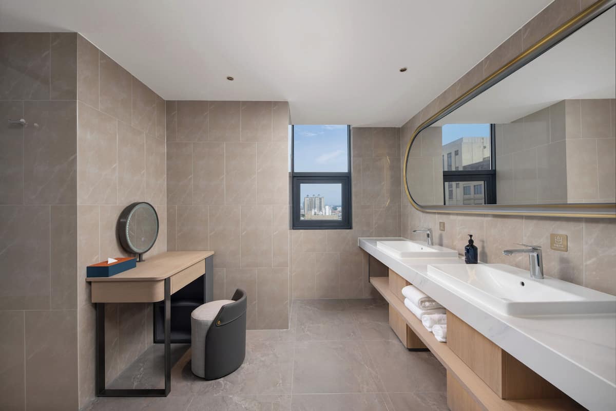 Een moderne badkamer met twee wastafels, een spiegel en een raam.