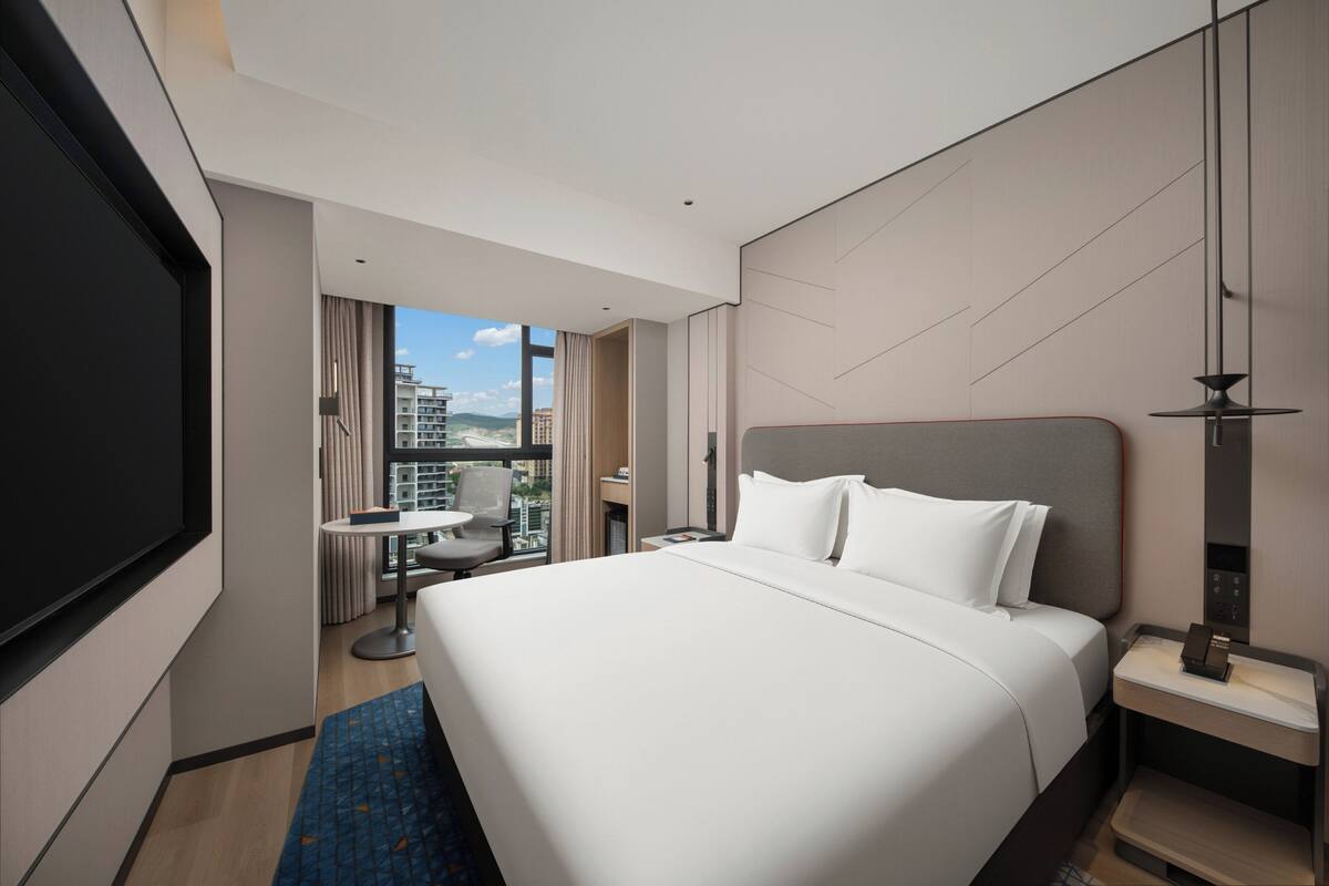Een moderne hotelkamer met een groot bed, een bureau, een stoel en een televisie.