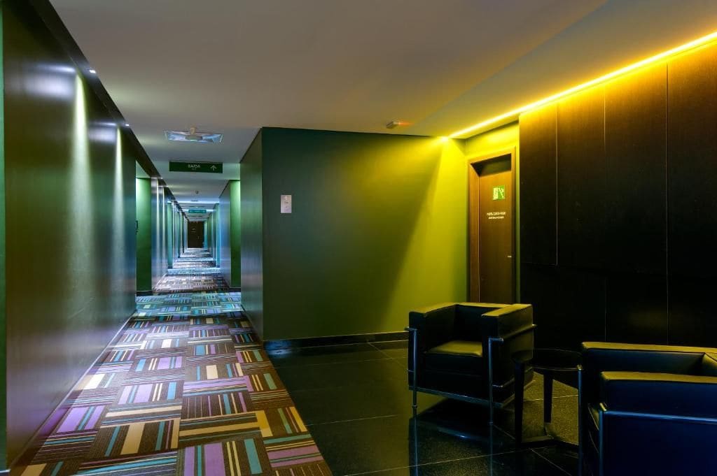 A hotel hallway with a patterned carpet, a reception desk, and a door with a sign.