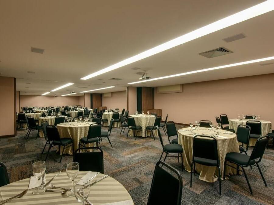 Ein großer Festsaal mit mehreren runden Tischen, jeweils mit Stühlen und Geschirr bestückt.