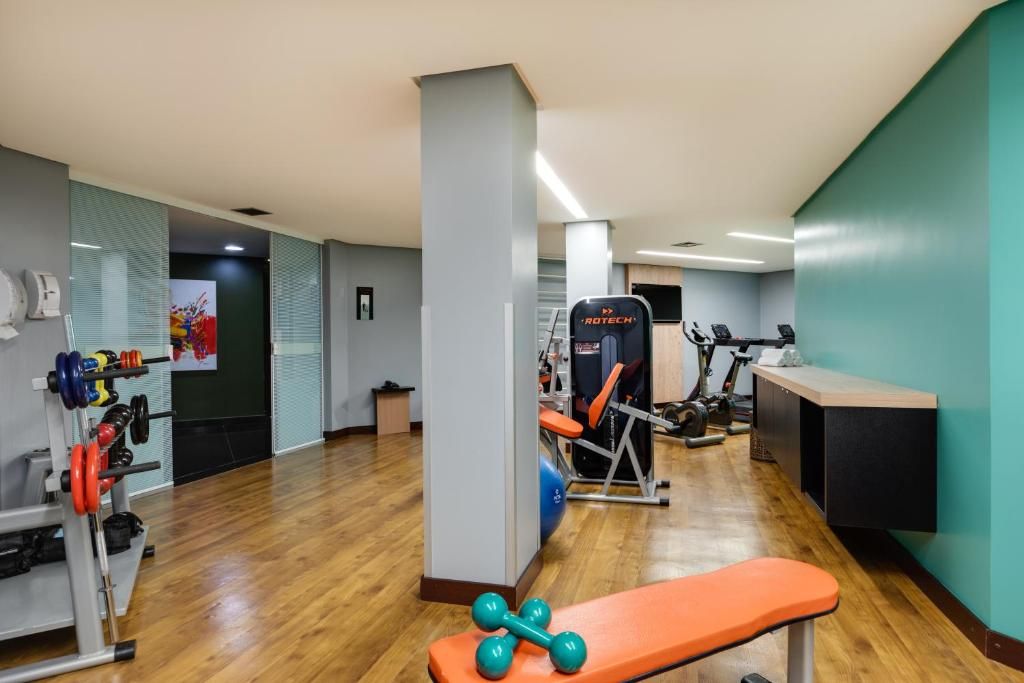A gym with weightlifting equipment, a bench, and cardio machines.