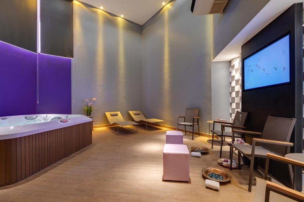 A spa room with a hot tub, lounge chairs, a massage table, and a projection screen.