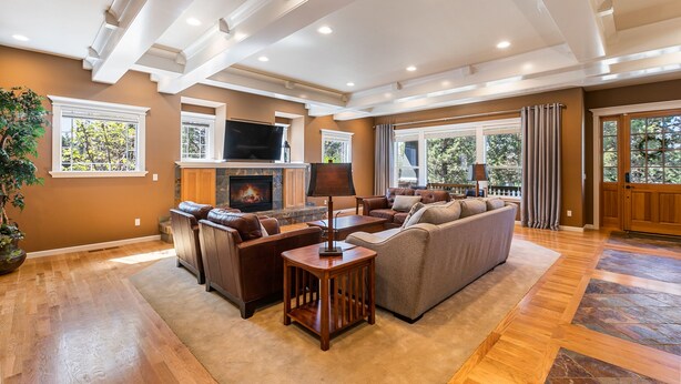 A spacious living room with a fireplace, leather sofas, a coffee table, and a large window with curtains. - Royal Oak Manor Lrg private home and yard sleeps 18! (Bend)
