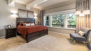 A bedroom with a large bed, a nightstand, a chair, and a window with curtains. - Royal Oak Manor Lrg private home and yard sleeps 18! (Bend)
