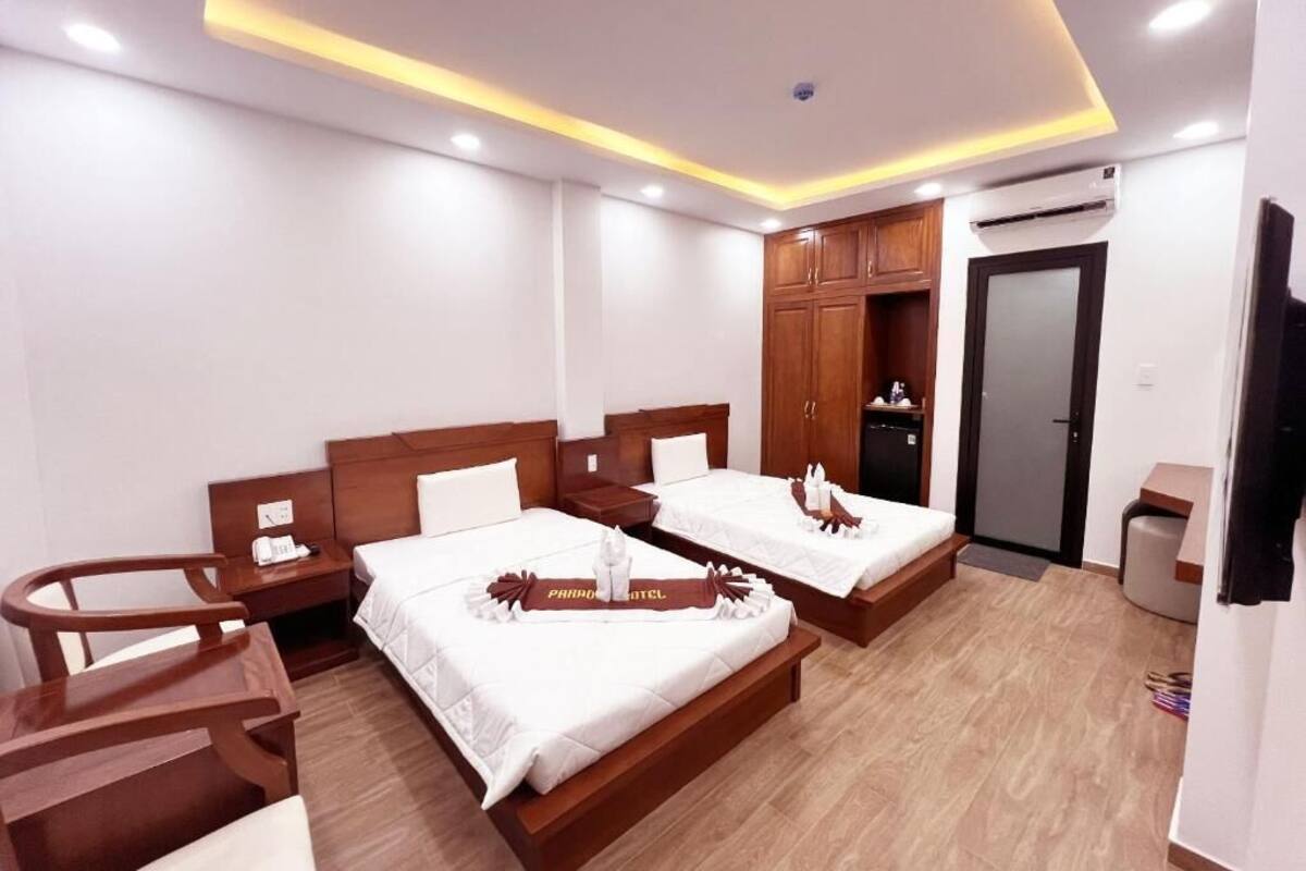 Habitación de hotel con dos camas, muebles de madera, un equipo de aire acondicionado y un televisor.