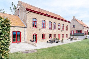 A brick building with red-framed windows and a tiled roof.
