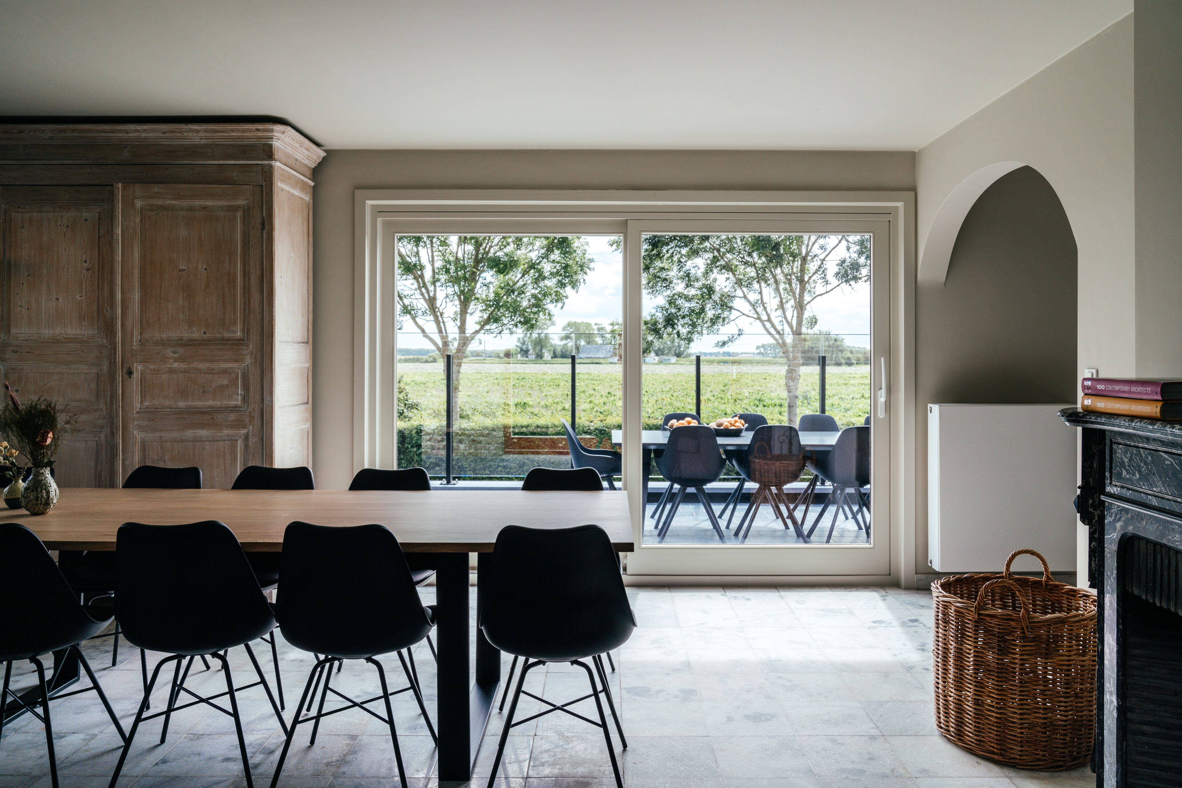 A dining area with a large table and chairs, a fireplace, and a view of the outdoors.
