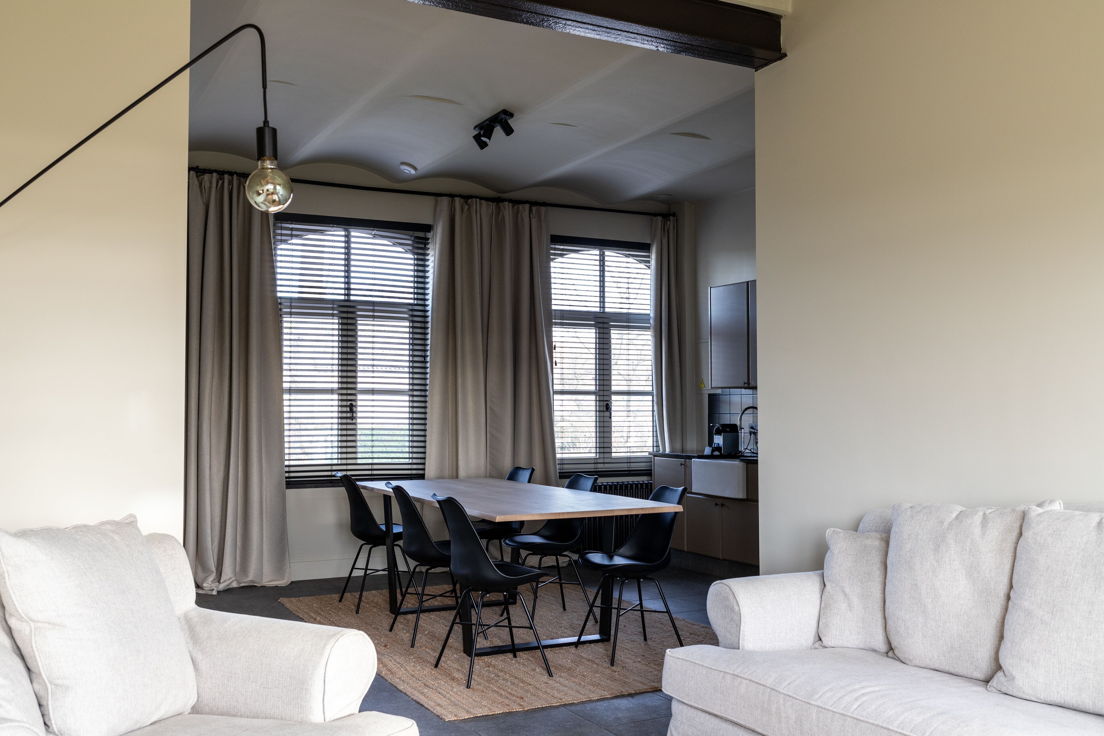 Ein modernes Wohnzimmer mit Esstisch, zwei Sofas und einer Küchenzeile.