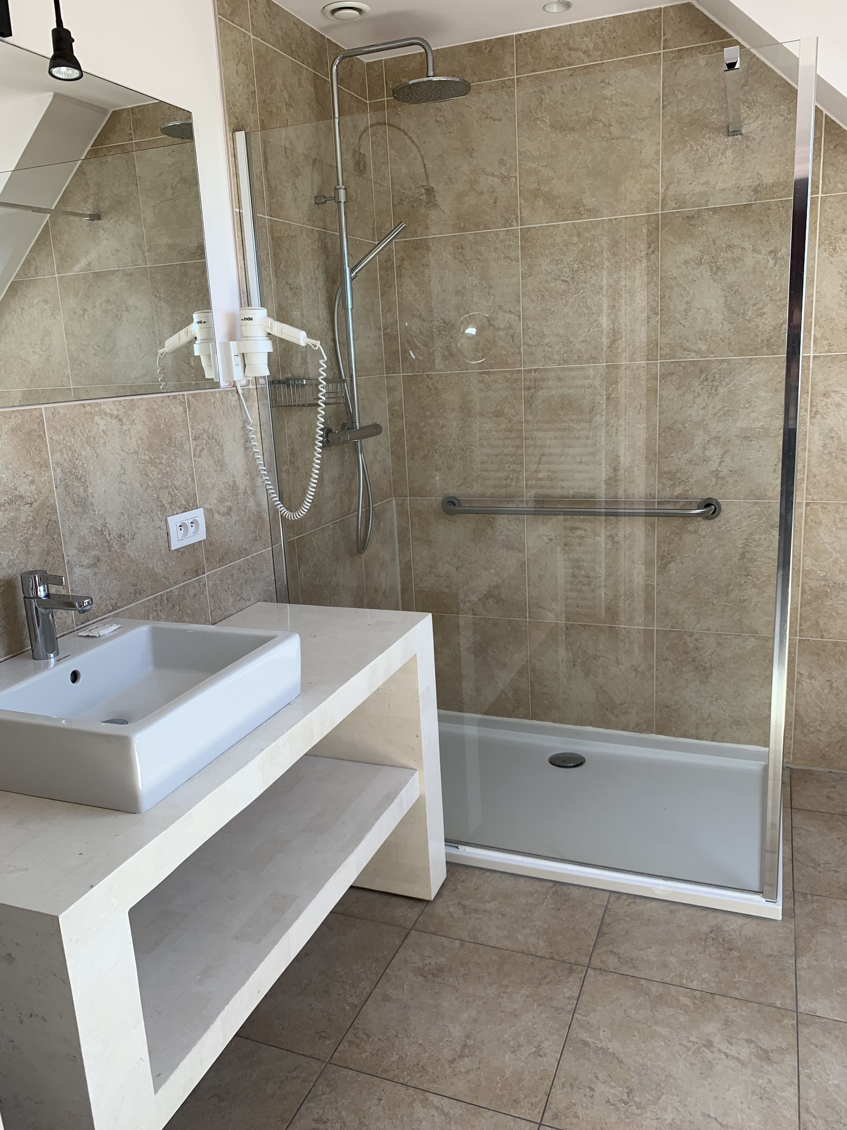 A modern bathroom with a shower, a sink, and a toilet.