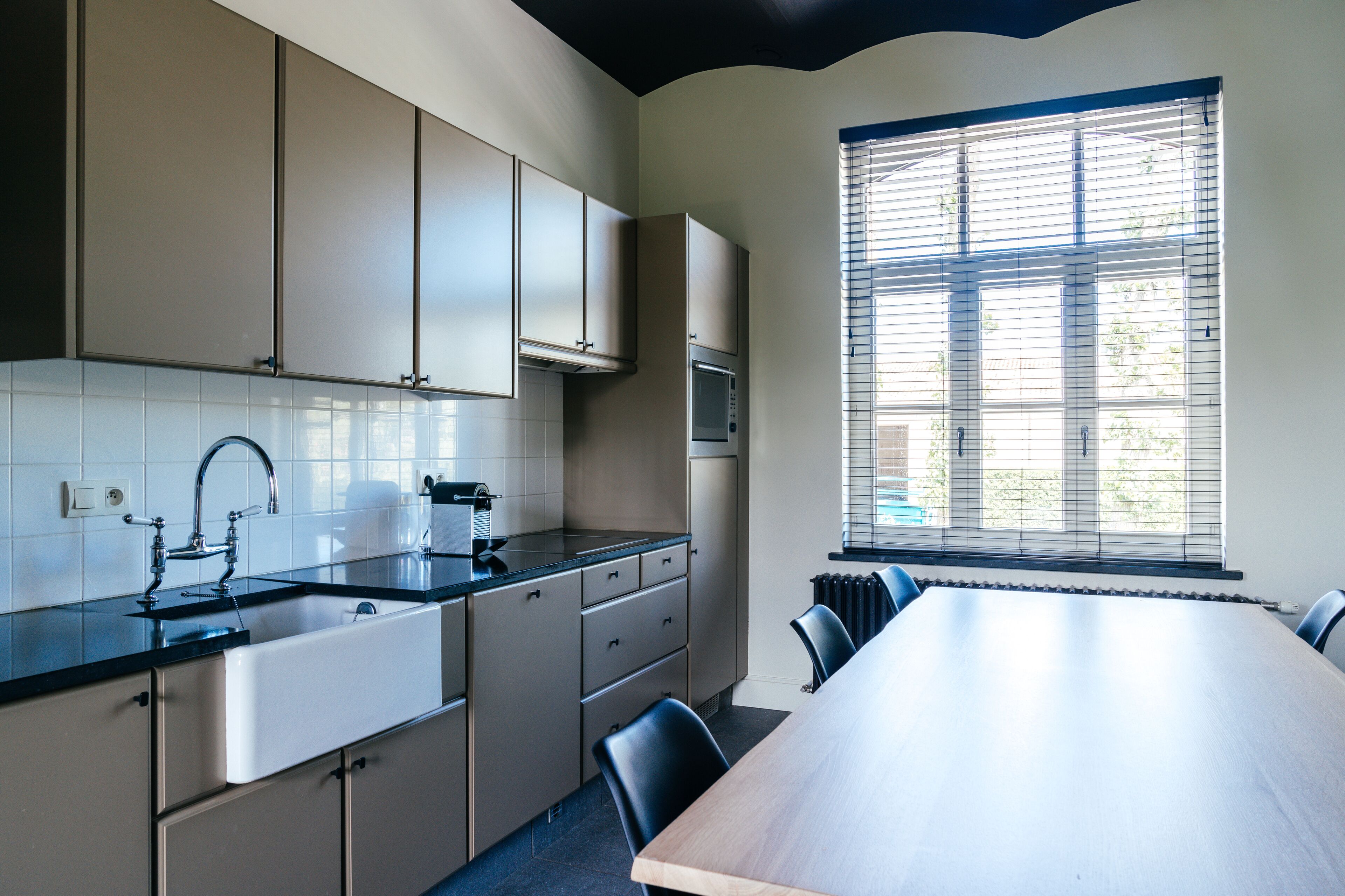 Una cocina moderna con una mesa comedor grande, armarios empotrados y una ventana con persianas.