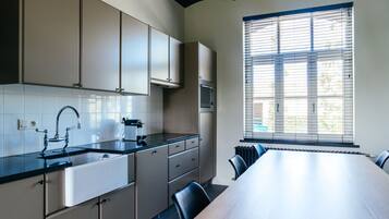 Una cocina moderna con una mesa comedor grande, armarios empotrados y una ventana con persianas.