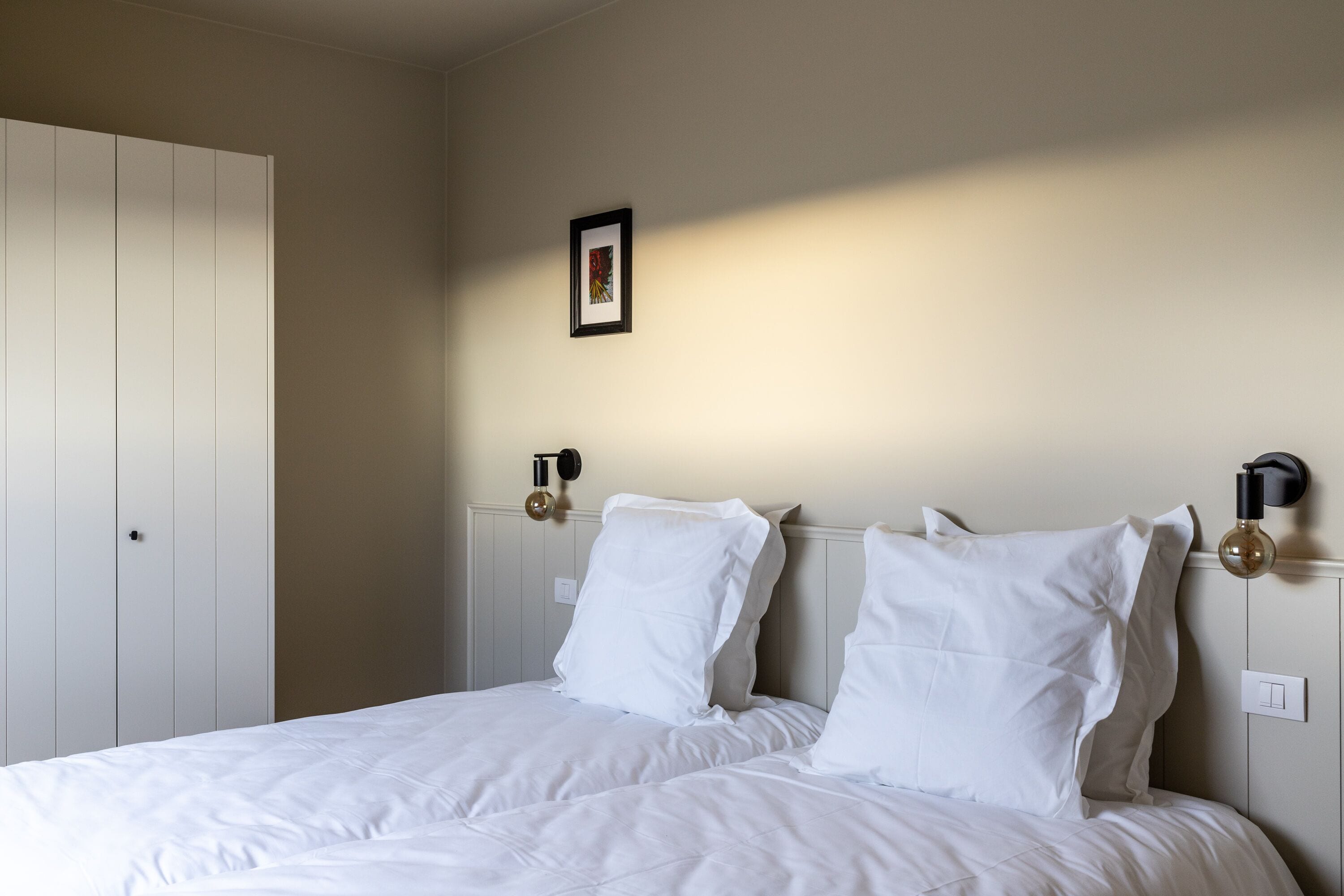 A bedroom with a bed, a wardrobe, and a wall-mounted light fixture.