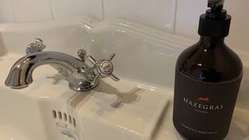 A bathroom sink with a faucet and a bottle of Hazegras shampoo.