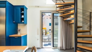 Une cuisine moderne avec des meubles bleus, un coin repas comprenant une table et des chaises, et un escalier en colimaçon.