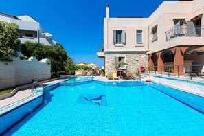 Ein Schwimmbecken mit klarem, blauem Wasser, umgeben von Gebäuden mit Balkonen und Außenplätzen.