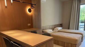 A modern hotel room with a wooden desk and two single beds. - Deluxe Studio – Comfort & Style for Two (Crete)