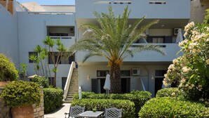 Un cortile con una palma, una scala e un’area salotto con tavolo e sedie.