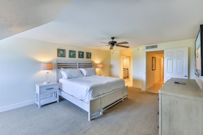 A bedroom with a bed, nightstands, a ceiling fan, and a door leading to another room. - SOUTH Villa 5310 - Three bedroom condo with Bay views (Captiva)