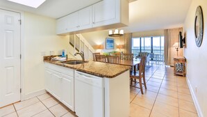 A kitchen with white cabinets, a dishwasher, and a dining area with a table and chairs. - SOUTH Villa 5310 - Three bedroom condo with Bay views (Captiva)