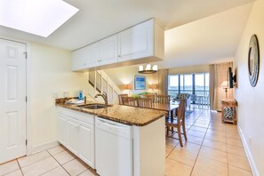 A kitchen with white cabinets, a dishwasher, and a dining area with a table and chairs.