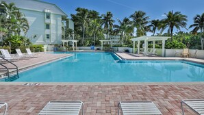 A swimming pool with lounge chairs, a covered area, and a building with a light-colored exterior. - SOUTH Villa 5310 - Three bedroom condo with Bay views (Captiva)