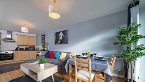 Una sala de estar moderna con comedor, una cocina al fondo y un amplio ventanal con vistas al exterior.