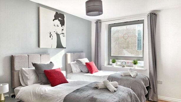 Un dormitorio moderno con dos camas, un ventanal grande y vistas a la ciudad.