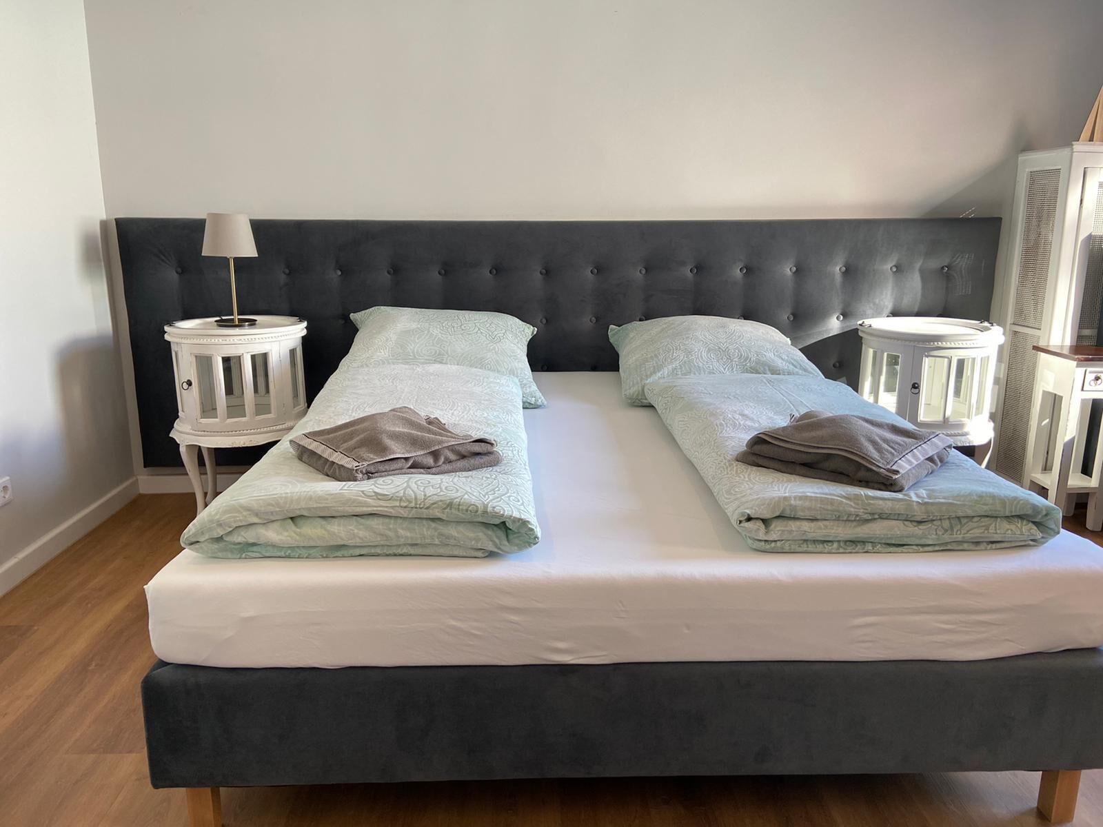 A double bed with a dark headboard, two bedside tables with lamps, and a light-colored patterned bedspread.