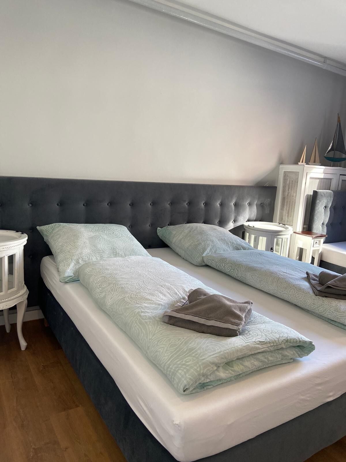 Uma cama de casal com cabeceira escura, duas mesas de cabeceira e um cobreleite estampado.