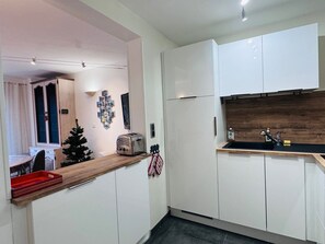 A modern kitchen with white cabinets, a wooden countertop, a built-in oven, and a sink with a wooden backsplash.