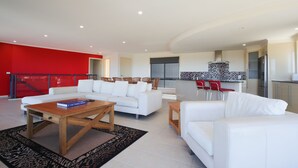 A modern living room with a white sofa, a wooden coffee table, and a red accent wall. - A Vista, Townhouse 1 (Forster)