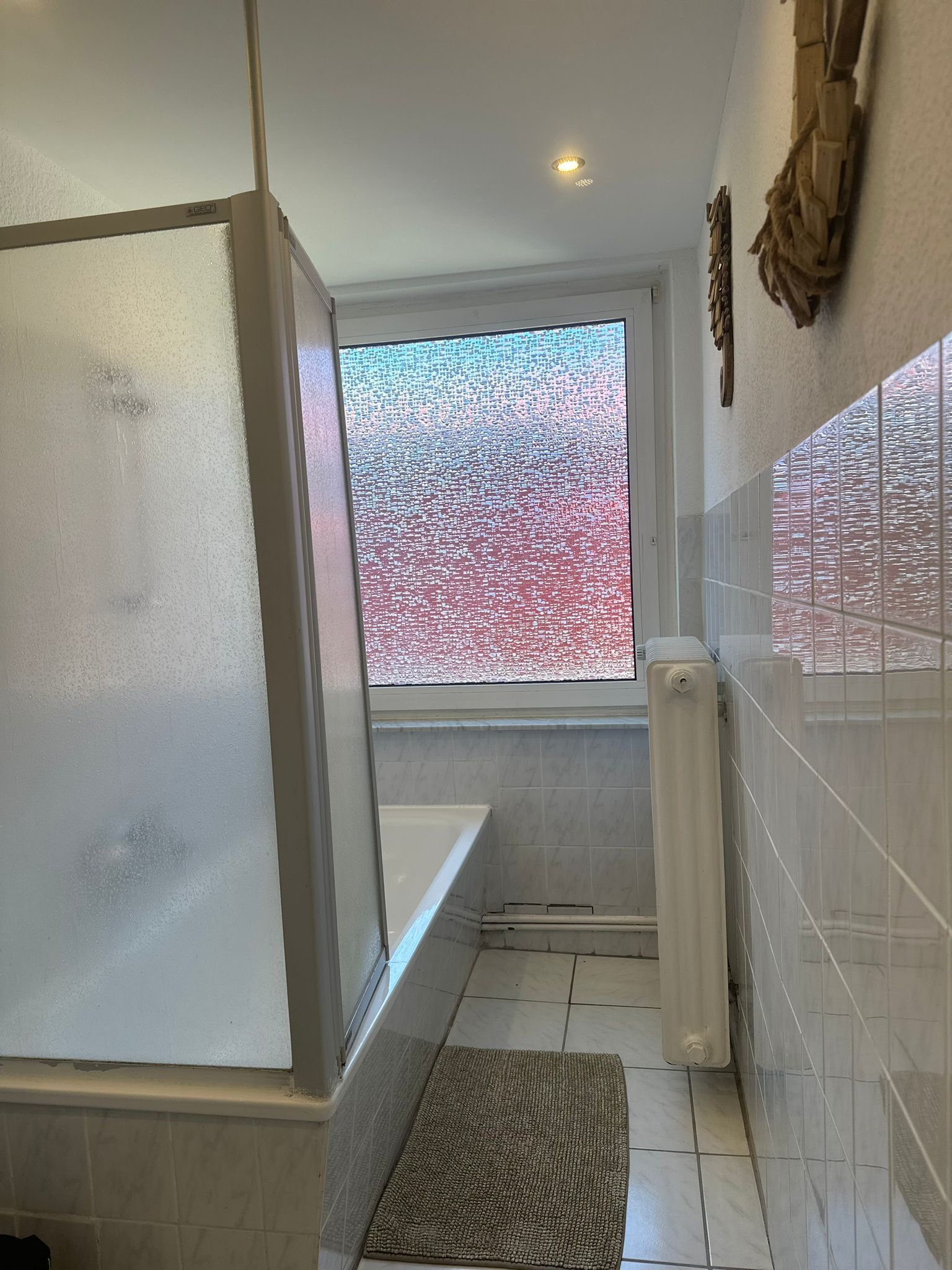 Een badkamer met een douche, een raam met uitzicht en een radiator.