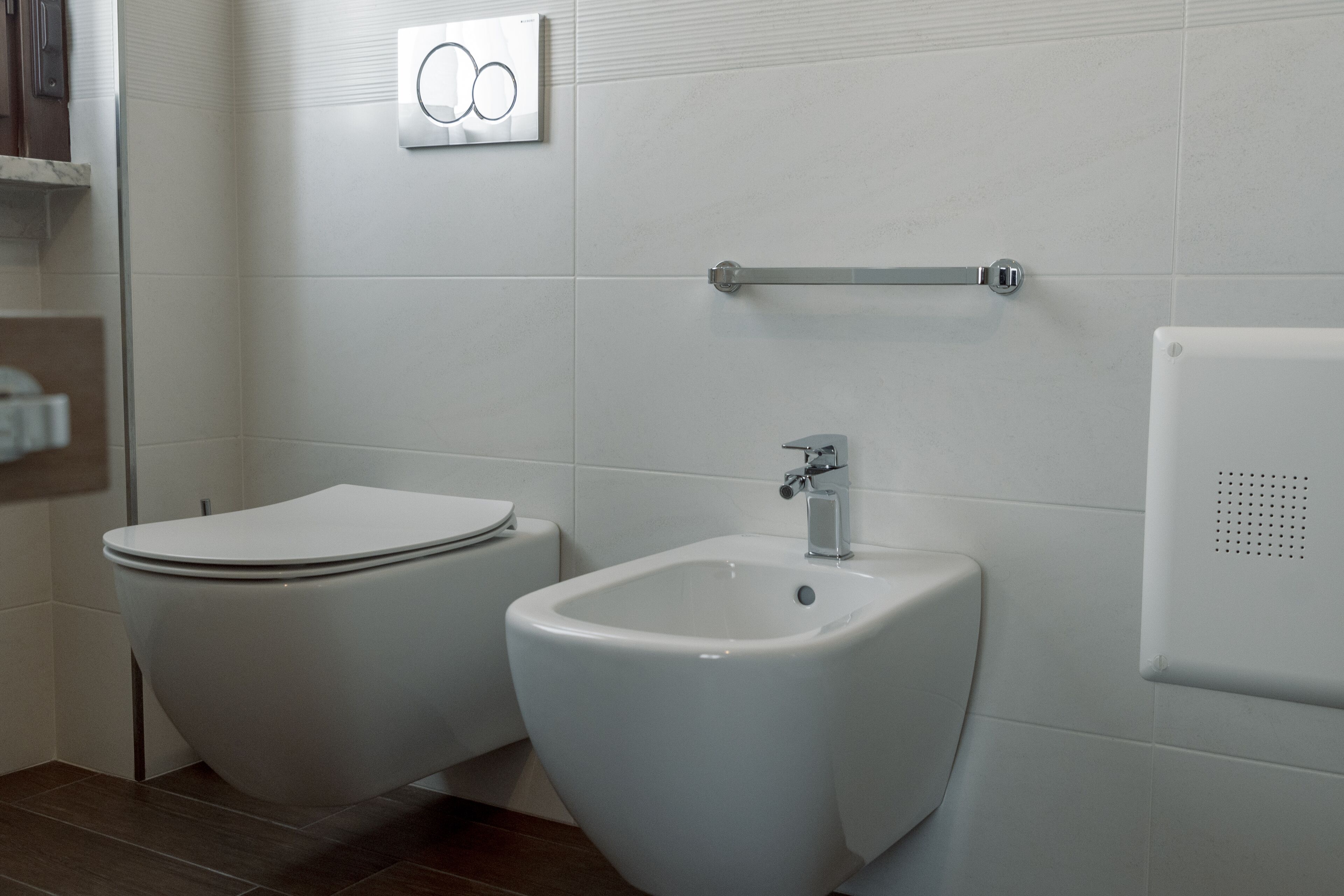 Une salle de bain moderne équipée de toilettes, d’un bidet et d’un porte-serviettes.