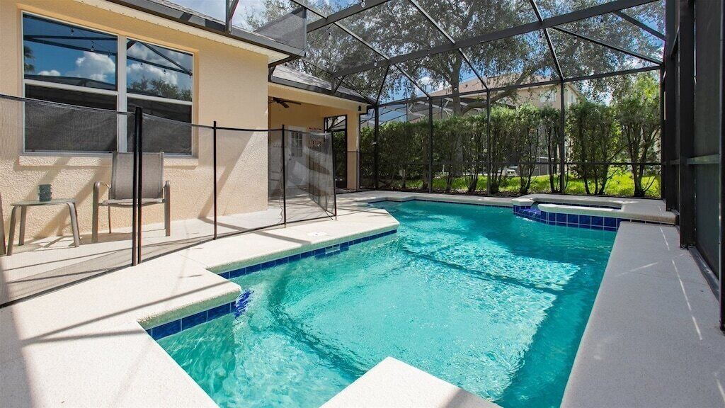 A swimming pool with a sunshade structure, a covered seating area, and a view of the surrounding greenery.