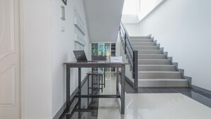 A modern hotel lobby with a staircase, a desk with a laptop, and a check-in counter. - K&k Apartment (Bang Phli)